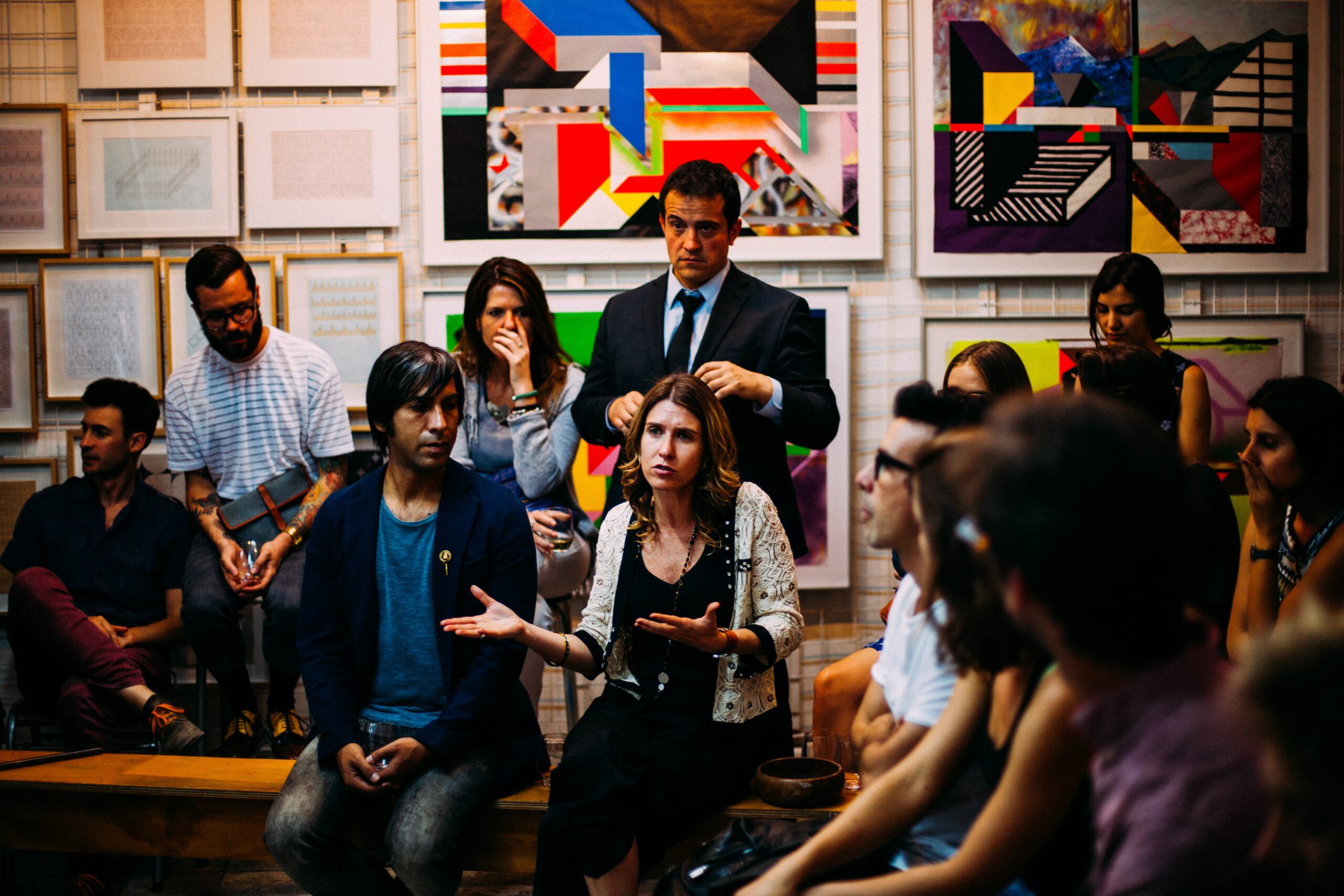 A group of young, diverse people, some sitting and some standing, having a serious group conversation