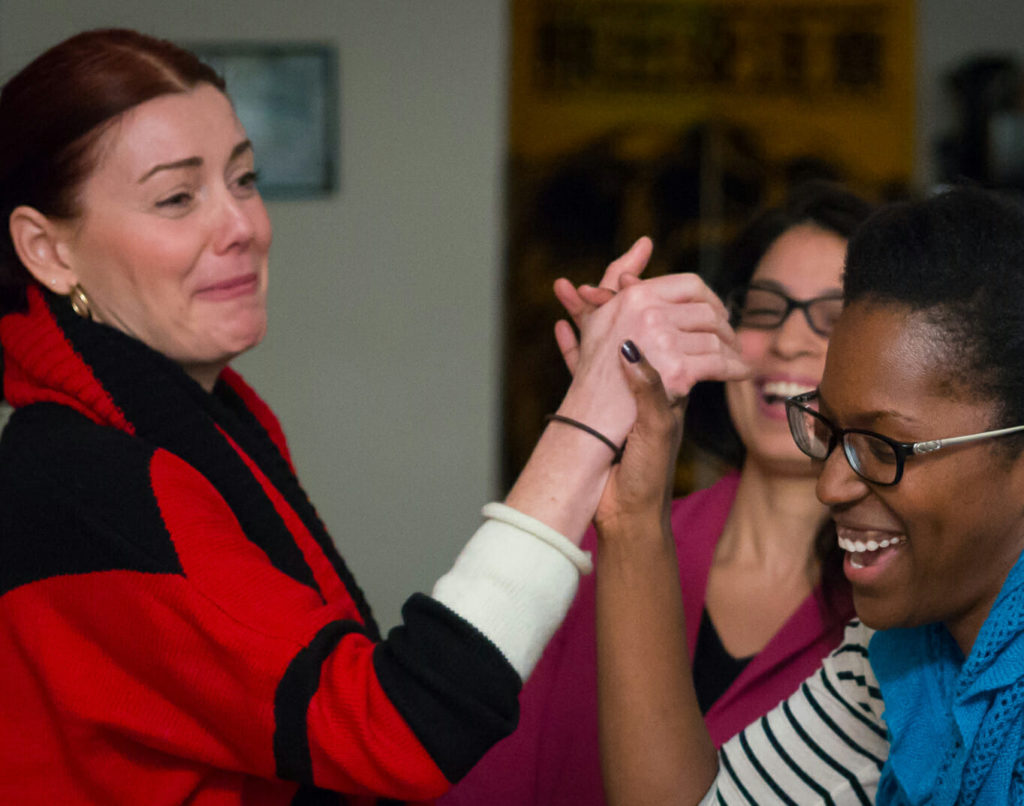 Two women laughing and high fiving each other